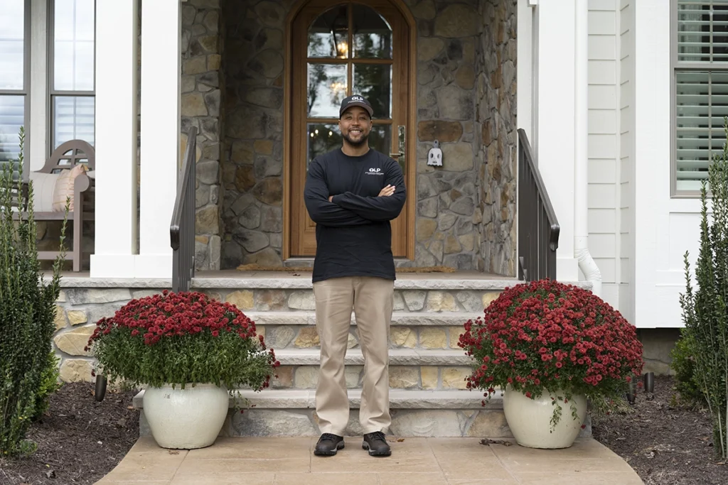 tech smiling in front of the front of a house